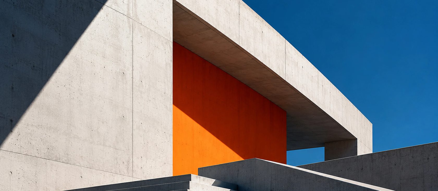 Volume orange encadré de béton, escaliers et ciel bleu
